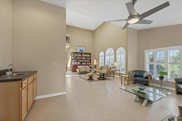 living room featuring high vaulted ceiling, baseboards, a ceiling fan, and light tile patterned flooring