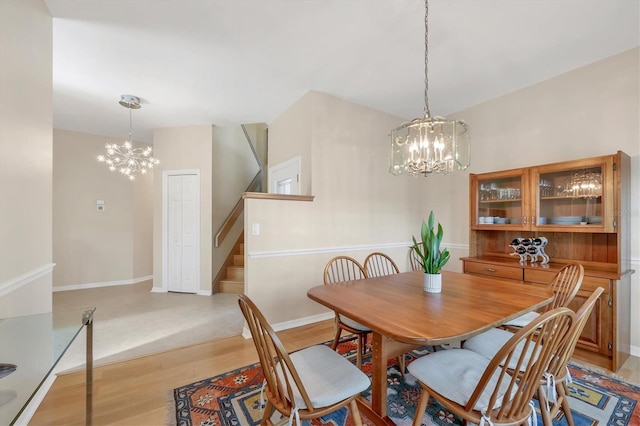 dining area featuring a chandelier, stairway, baseboards, and light wood-style floors