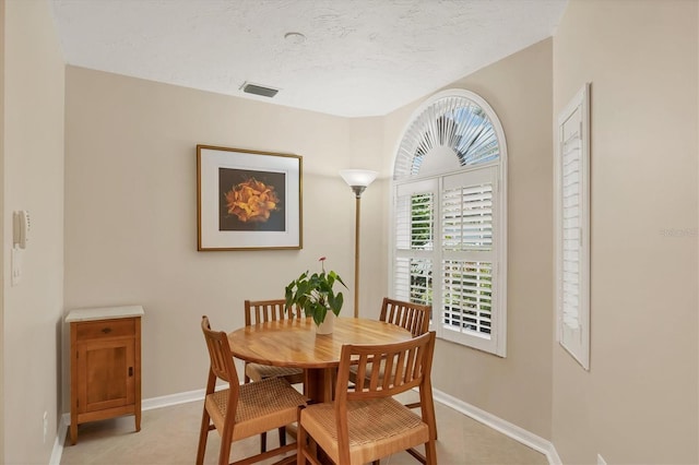 dining area featuring visible vents, a textured ceiling, and baseboards