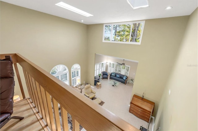 hall with a skylight, a towering ceiling, an upstairs landing, and recessed lighting