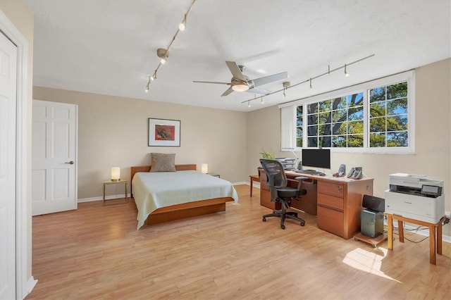 bedroom with light wood-type flooring, a ceiling fan, and baseboards