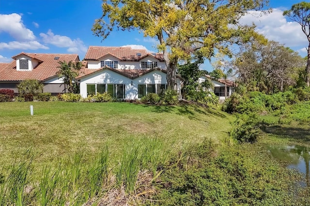 mediterranean / spanish-style home with a tile roof and a front lawn