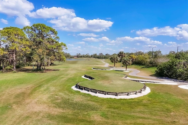 view of property's community with view of golf course and a lawn