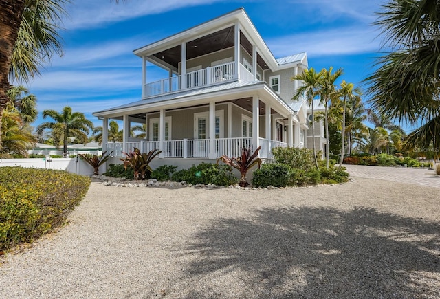 view of front facade featuring covered porch, a standing seam roof, metal roof, a balcony, and fence