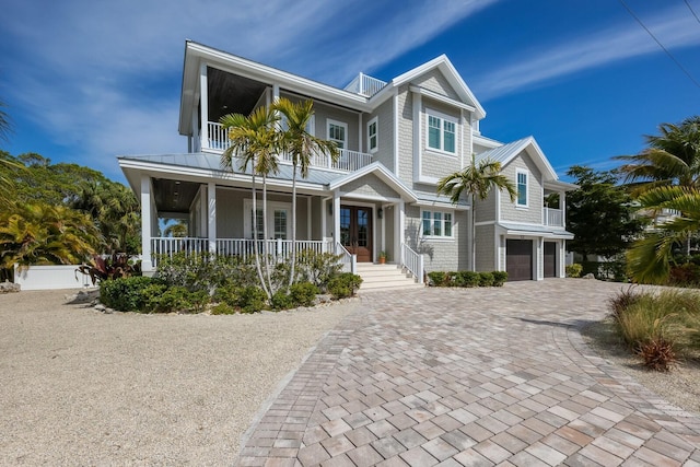 view of front facade featuring covered porch, metal roof, decorative driveway, and a balcony