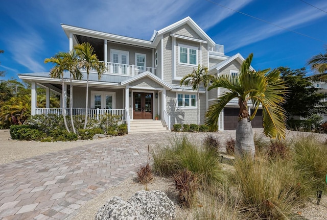 view of front of property with covered porch, french doors, and a balcony