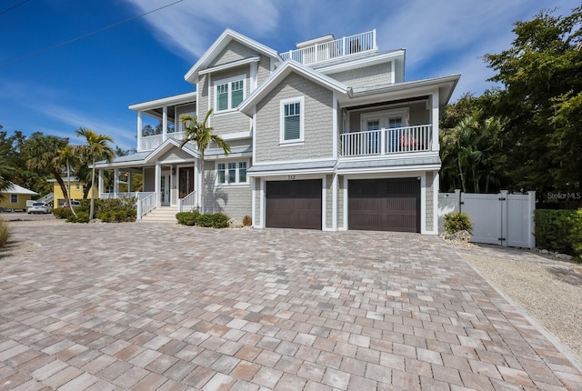 view of front of house featuring a balcony, covered porch, a gate, fence, and decorative driveway