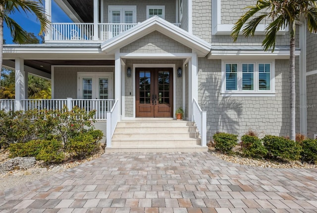 entrance to property featuring french doors, a porch, and a balcony