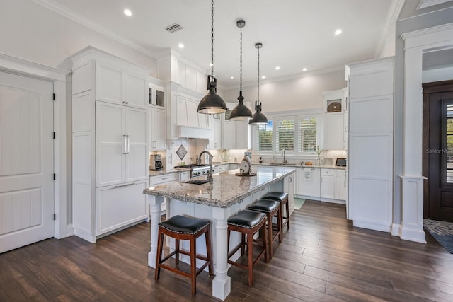 kitchen with a kitchen island with sink, a sink, visible vents, and white cabinets