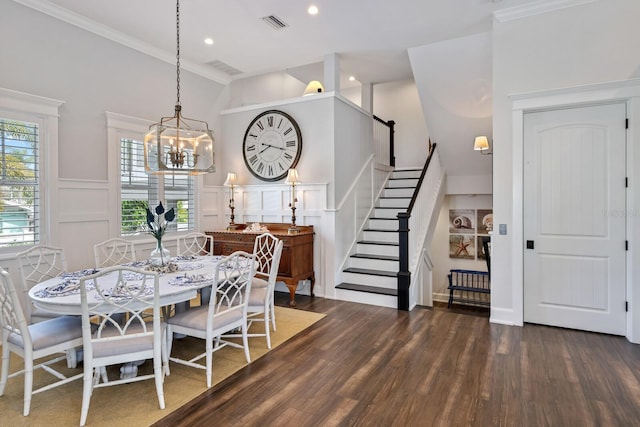 dining room featuring dark wood-style floors, visible vents, a decorative wall, ornamental molding, and stairs