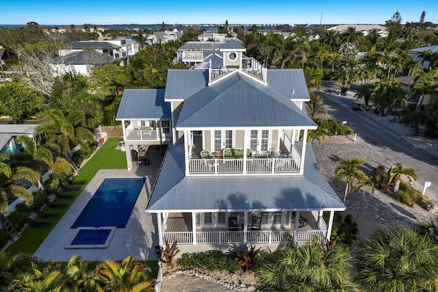 back of house with a balcony, a patio area, a fenced backyard, and metal roof