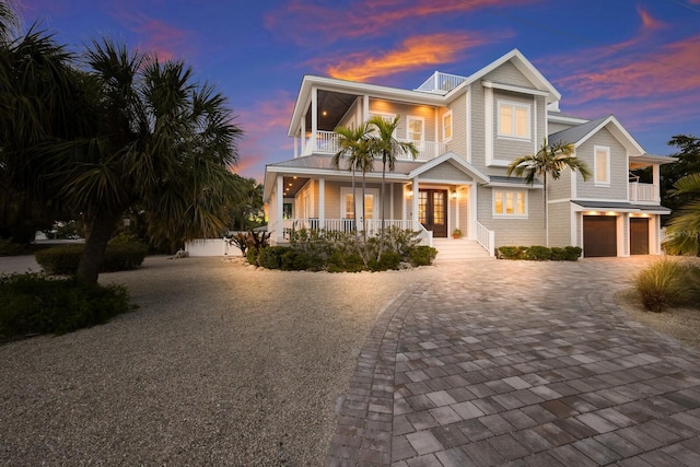 view of front of home with a porch, a balcony, a garage, french doors, and decorative driveway