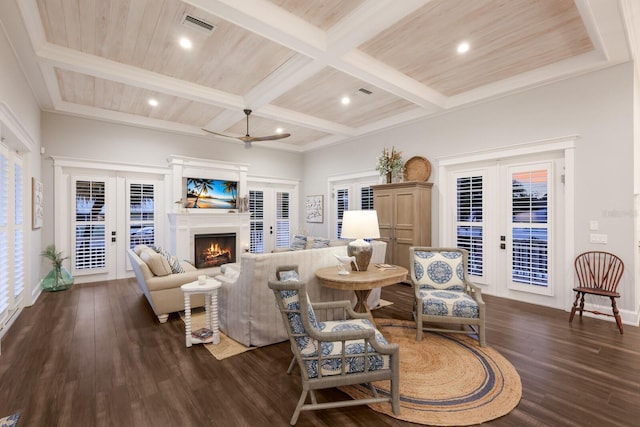 living area with dark wood-style floors, a lit fireplace, beamed ceiling, and french doors