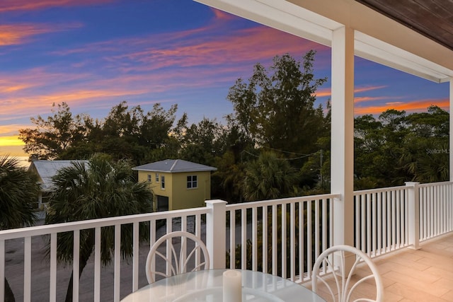 balcony at dusk featuring outdoor dining area