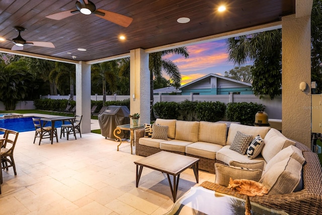 patio terrace at dusk featuring a fenced in pool, outdoor lounge area, area for grilling, a ceiling fan, and fence