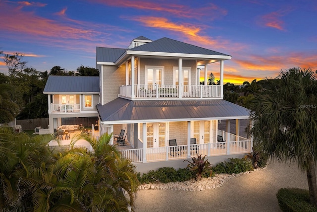 rear view of property featuring covered porch, french doors, and a balcony