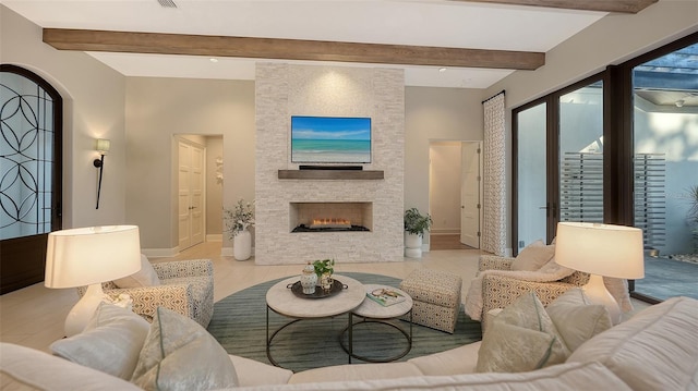 living area featuring beam ceiling, a fireplace, and baseboards