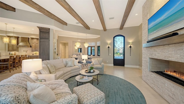 living area featuring visible vents, baseboards, beamed ceiling, light tile patterned floors, and a stone fireplace