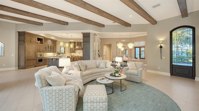 living area featuring visible vents, baseboards, light tile patterned flooring, arched walkways, and a notable chandelier