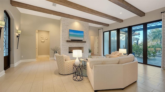 living area with visible vents, beamed ceiling, a fireplace, and baseboards