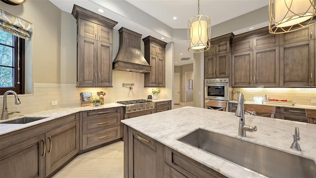 kitchen featuring stainless steel gas stovetop, light stone countertops, custom range hood, and a sink