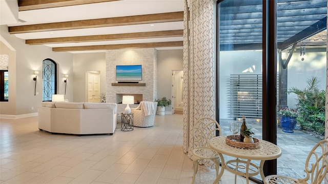 living area featuring beamed ceiling, a fireplace, and baseboards