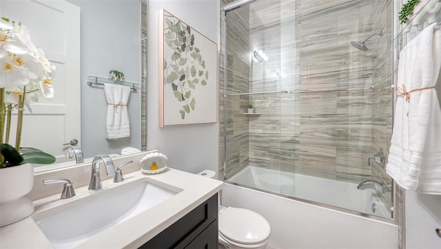 full bath with toilet, vanity, and shower / bath combination with glass door