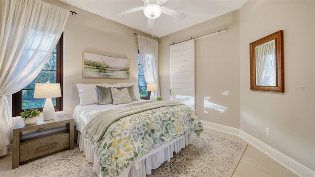 bedroom featuring a barn door, baseboards, and a ceiling fan