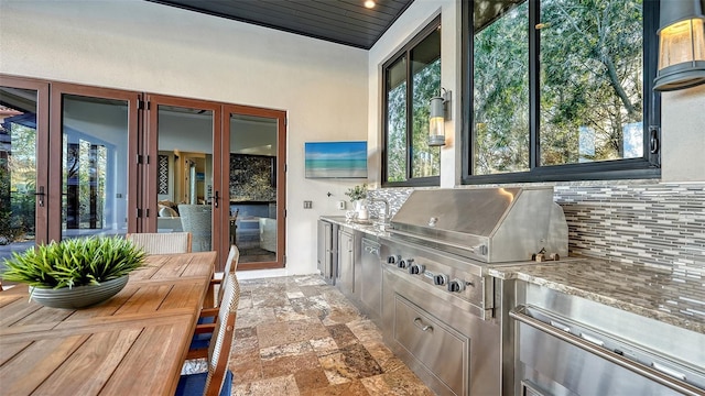 kitchen featuring decorative backsplash, stone tile floors, and stainless steel counters