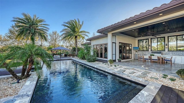 outdoor pool with a ceiling fan and a patio area