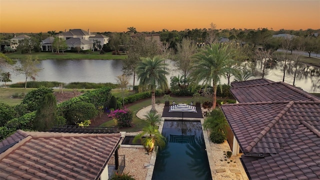 aerial view at dusk featuring a water view