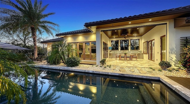 rear view of house featuring a tile roof, a patio area, and stucco siding