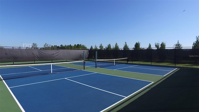 view of tennis court featuring community basketball court and fence