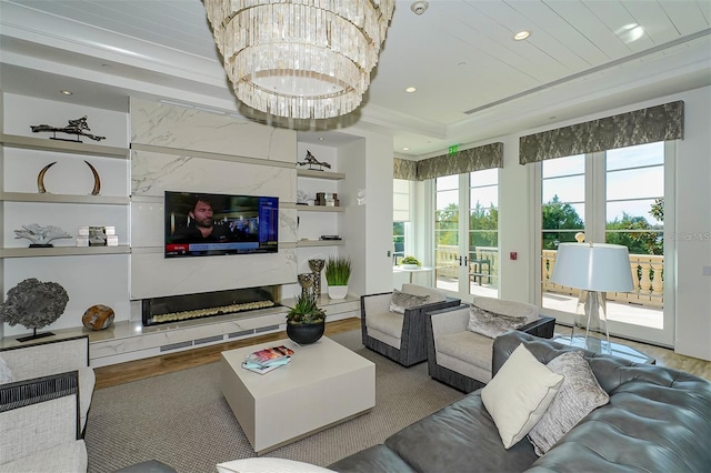 living room with built in shelves, wood finished floors, a premium fireplace, french doors, and a chandelier