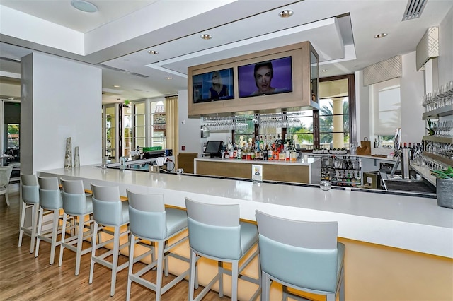 bar with visible vents, a healthy amount of sunlight, wood finished floors, and indoor wet bar