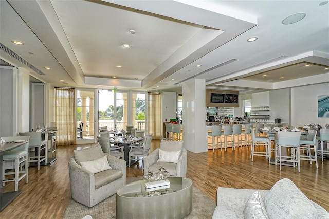 living area with recessed lighting, french doors, a tray ceiling, and wood finished floors