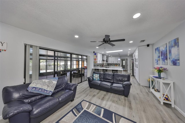 living room with a textured ceiling, light wood-type flooring, and visible vents