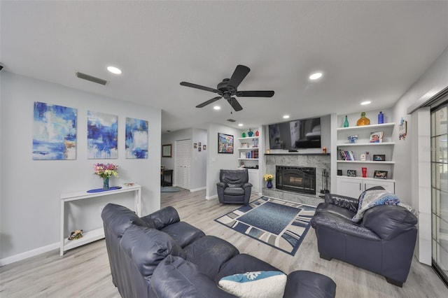 living area with light wood finished floors, recessed lighting, baseboards, visible vents, and a high end fireplace