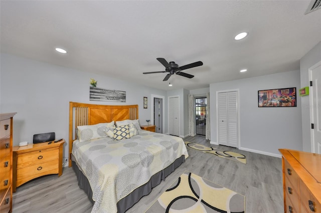 bedroom with recessed lighting, visible vents, baseboards, light wood-style floors, and multiple closets