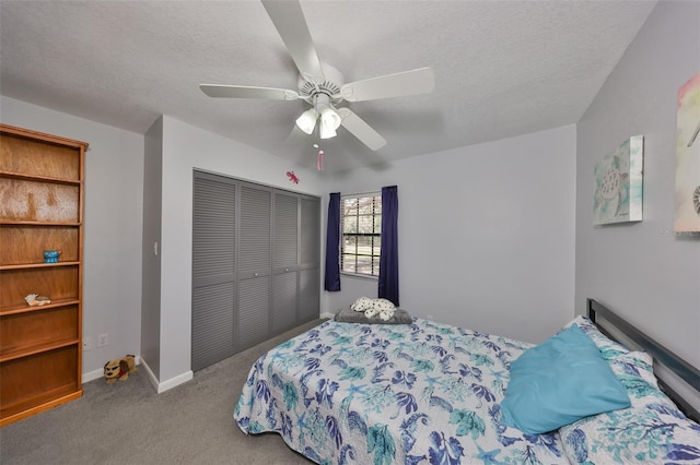 carpeted bedroom featuring ceiling fan, a closet, baseboards, and a textured ceiling