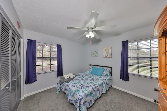 carpeted bedroom with ceiling fan, a textured ceiling, baseboards, and a closet