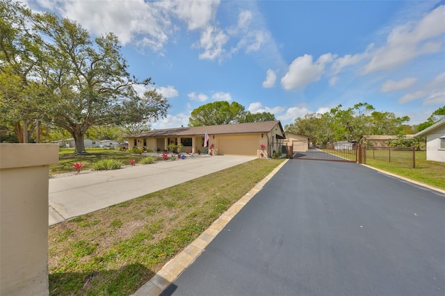 view of front facade with driveway, an attached garage, a gate, fence, and a front yard