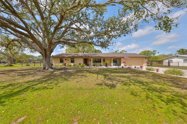 single story home with a garage, a front lawn, fence, and stucco siding