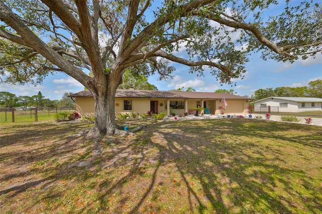 ranch-style house featuring a garage, fence, a front lawn, and stucco siding