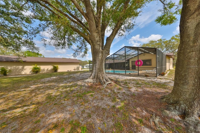 view of yard featuring glass enclosure and an outdoor pool