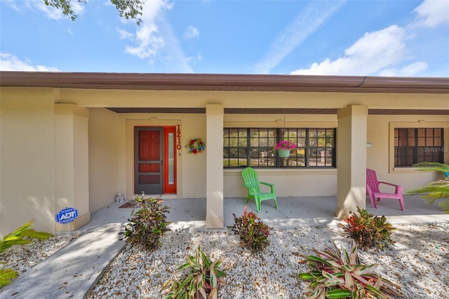 entrance to property with covered porch and stucco siding