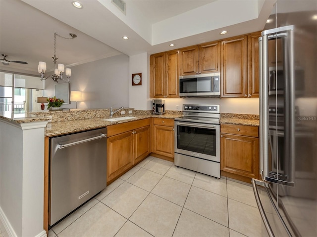 kitchen with brown cabinets, stainless steel appliances, visible vents, a sink, and a peninsula