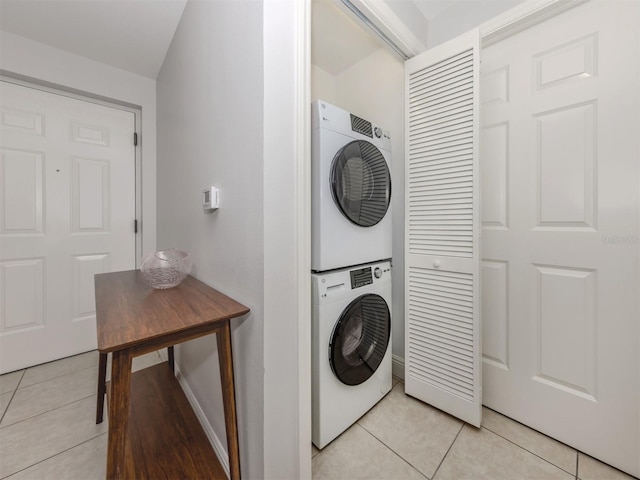 washroom featuring light tile patterned floors, stacked washer and dryer, and laundry area