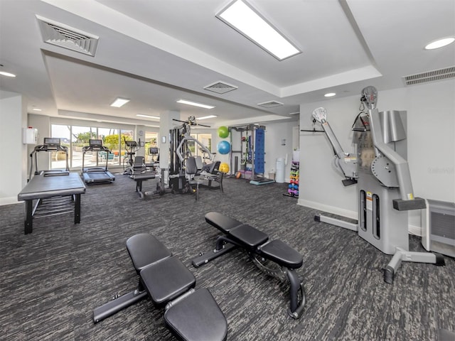 exercise room with visible vents and a tray ceiling