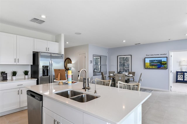 kitchen with visible vents, an island with sink, stainless steel appliances, light countertops, and a sink